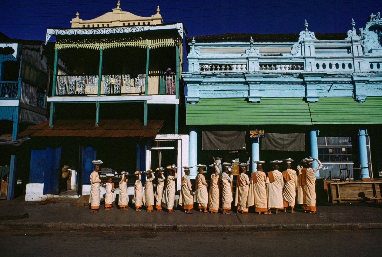 Monjas budistas de distintas edades desfilan por la acera pidiendo limosna. Maymyo, Birmania. de James L Stanfield