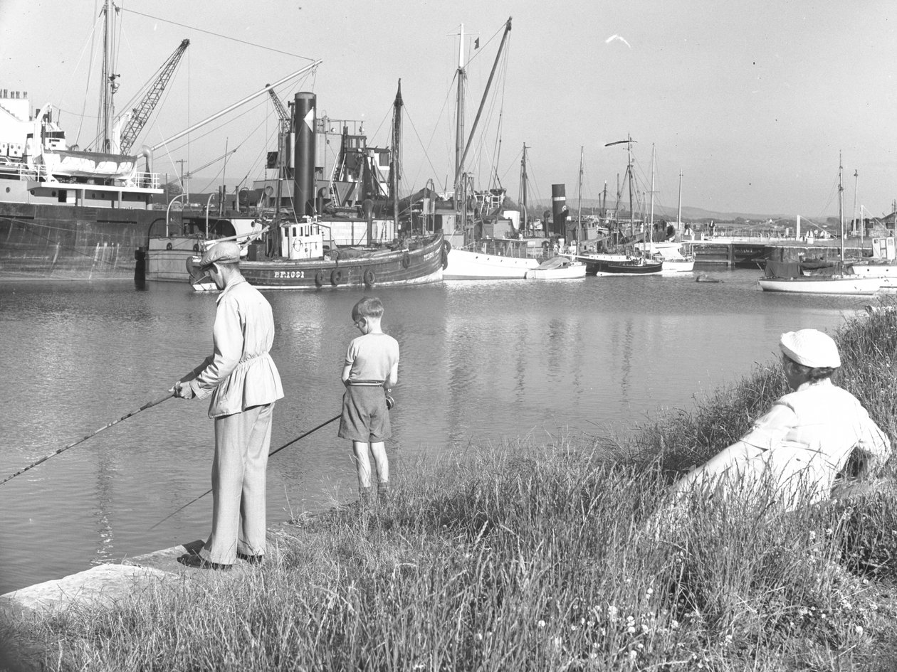 Un hombre y un niño pescando en Glasson Dock mientras una dama marina; paisaje marino; ted detrás mira, varios barcos amarrados de Joseph Hardman