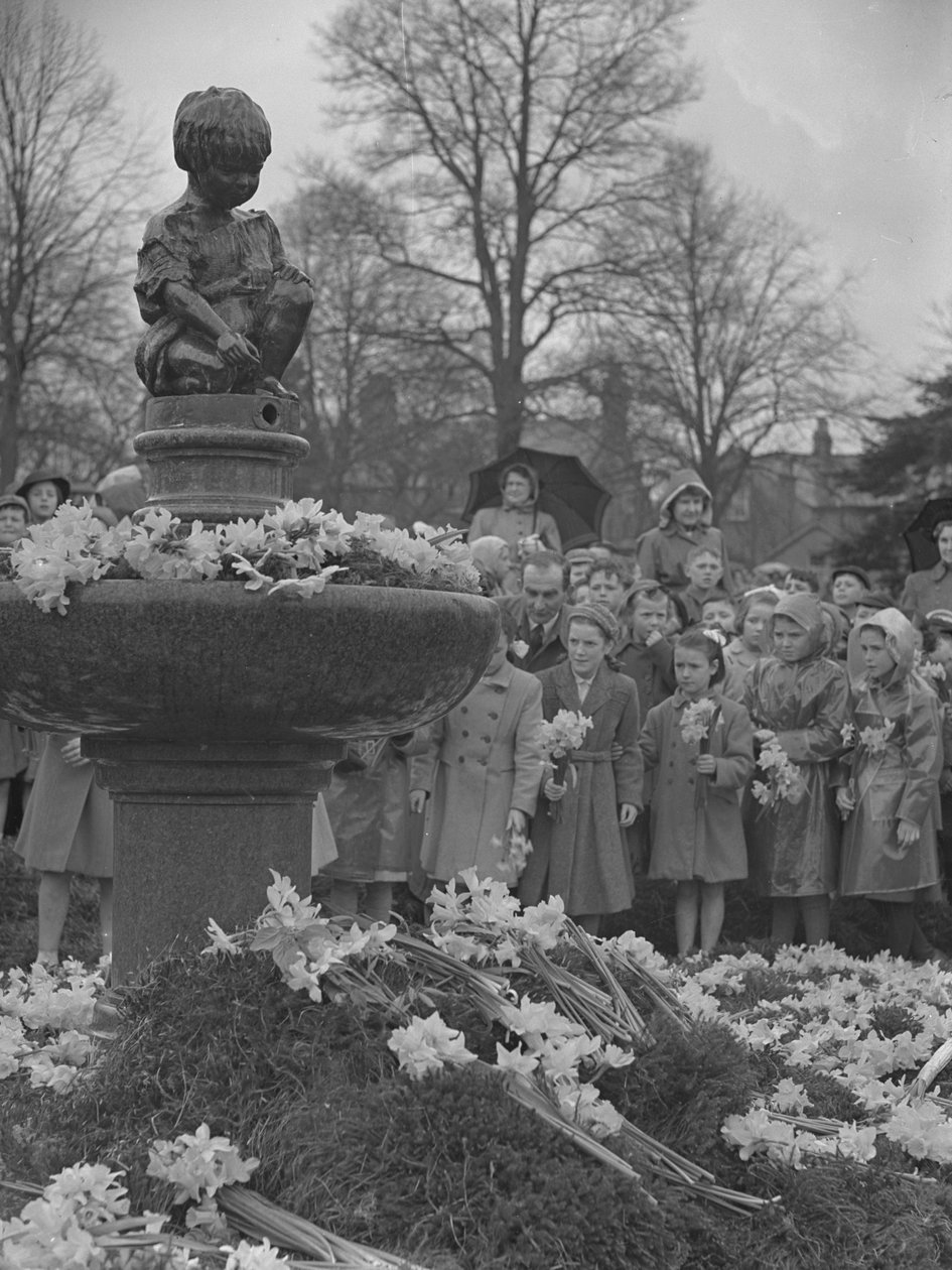 Niños colocando ramos de narcisos en una fuente con una estatua encima de Joseph Hardman
