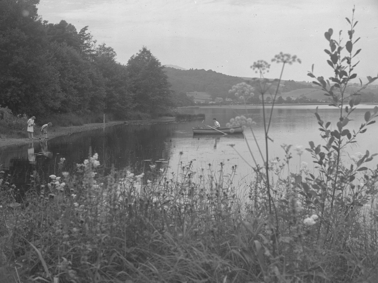 Hombre pescando en una barca en Estwaite Water y dos niñas al borde del agua de Joseph Hardman
