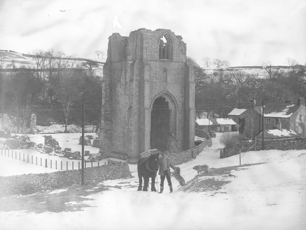 Hombre con caballo y dos perros frente a los restos de la Abadía de Shap en la nieve de Joseph Hardman