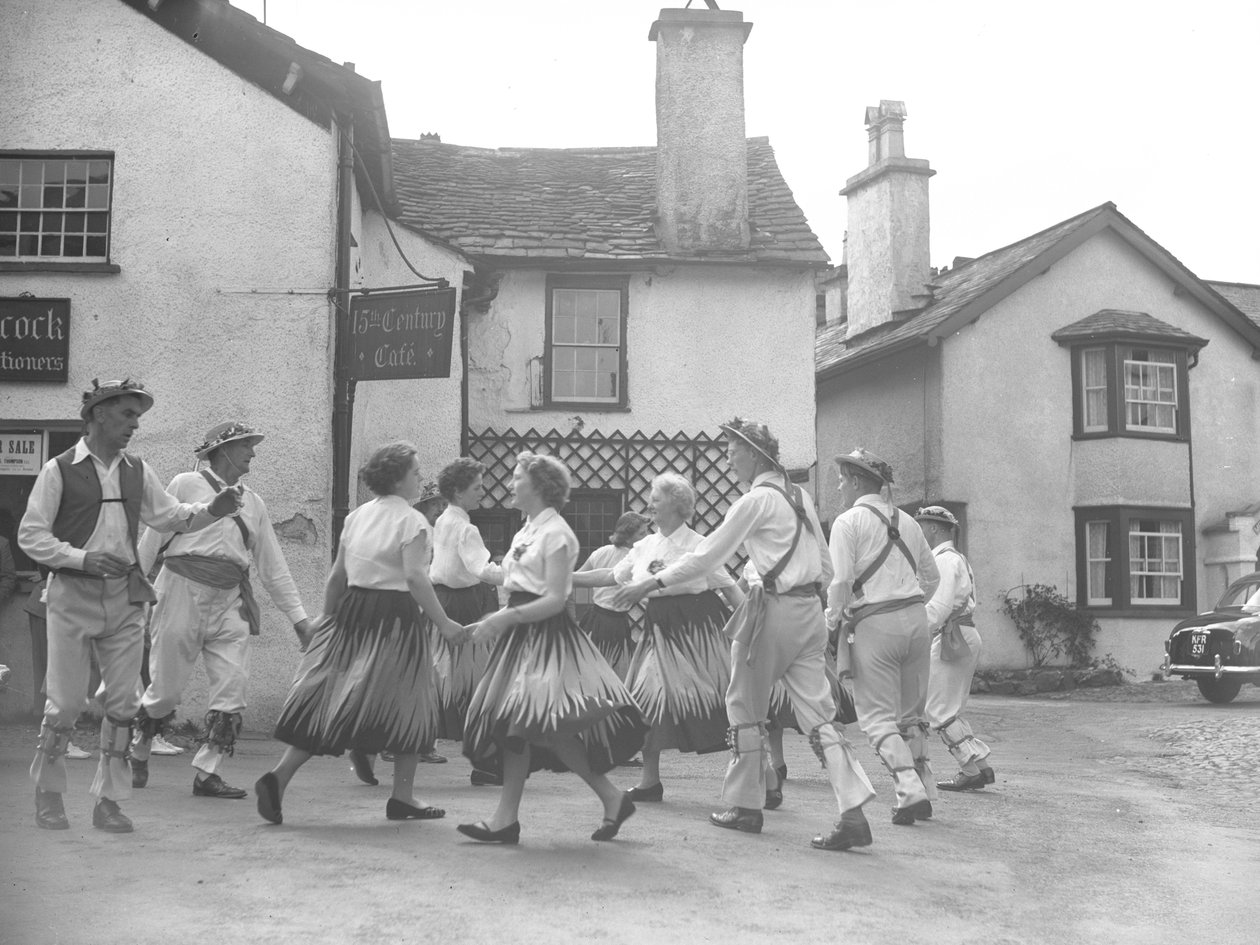 Hombres y mujeres bailando en Hawkshead con el cartel de 