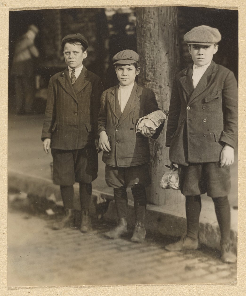 [Tres chicos en la calle de la ciudad en bragas y gorras] de Lewis W. Hine
