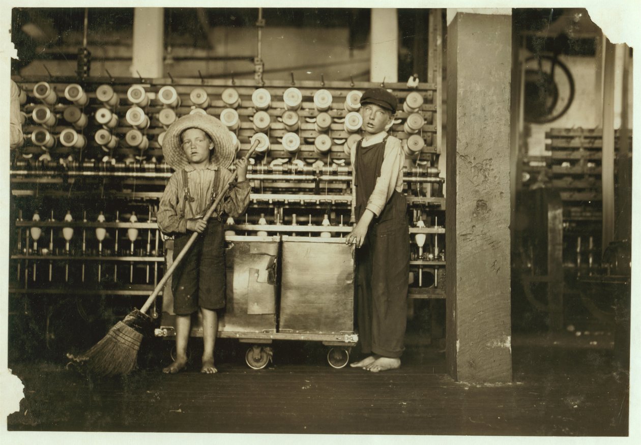 Ronald Webb de 12 años y Frank Robinson de 7 años, hijo del jefe de cardado, que barre y despeja (limpia bobinas llenas) en Roanoke Cotton Mills, Virginia, 1911 de Lewis Wickes Hine