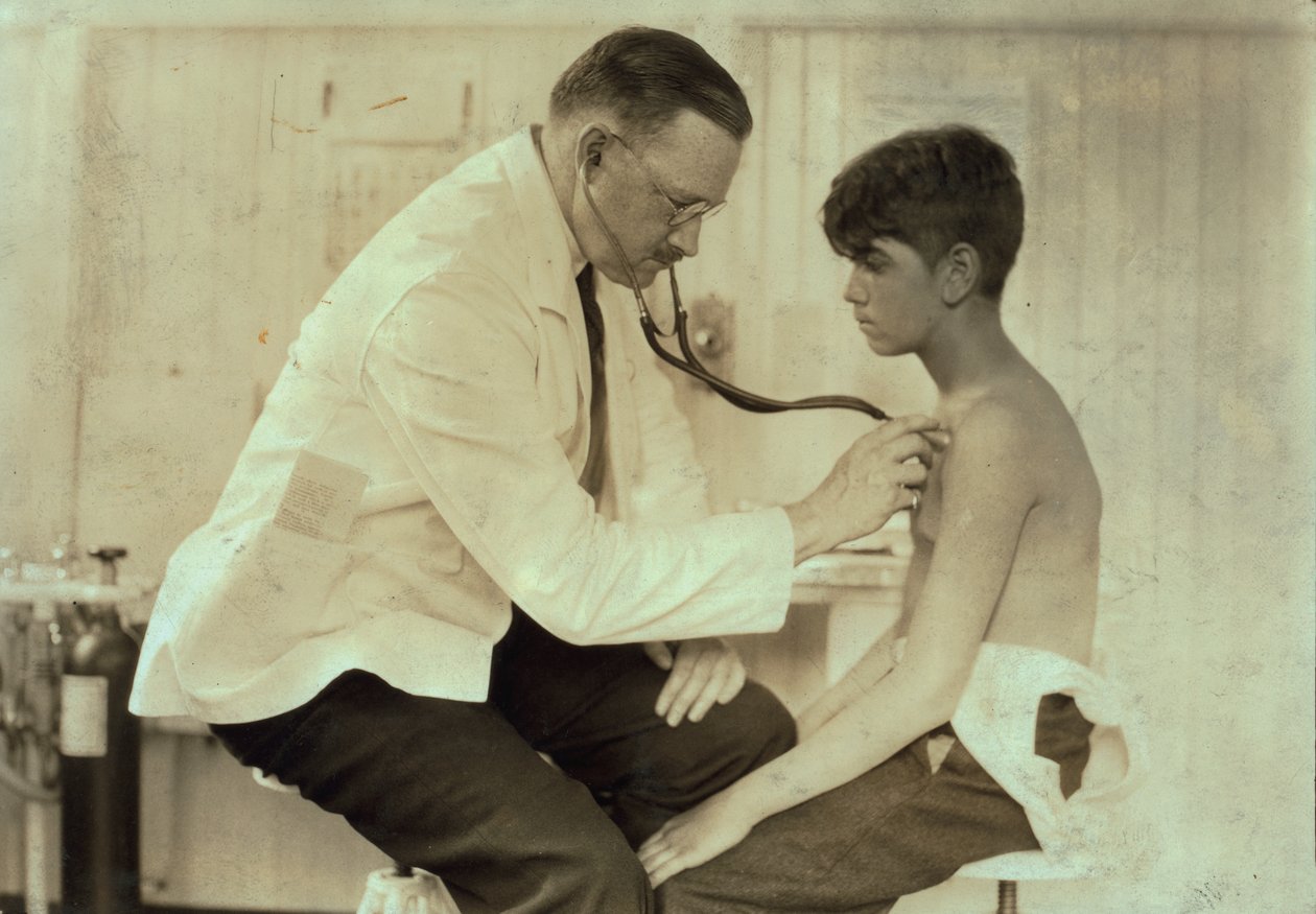Un médico examina a un joven trabajador en Cheney Silk Mills, South Manchester, Connecticut, hacia 1924 (fotografía en blanco y negro). de Lewis Wickes Hine