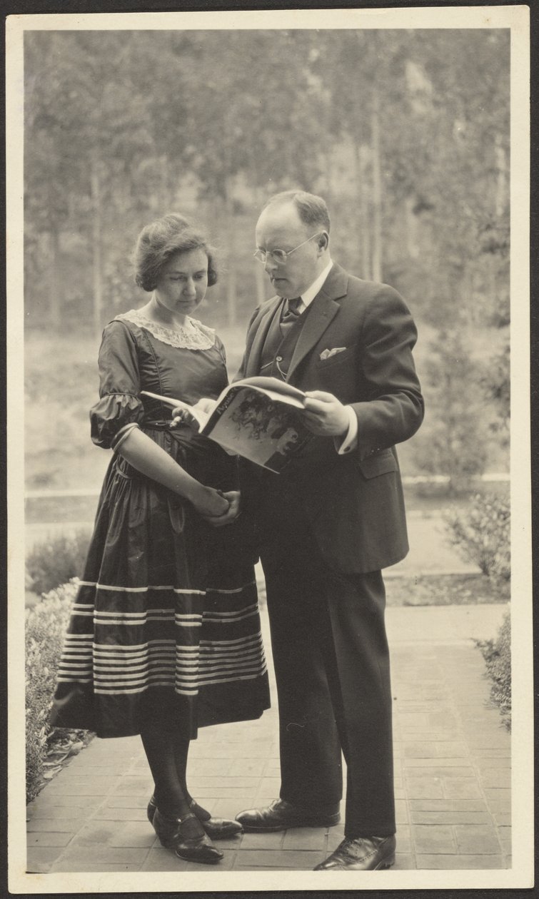 [Hombre y mujer de pie al aire libre con una revista] de Louis Fleckenstein