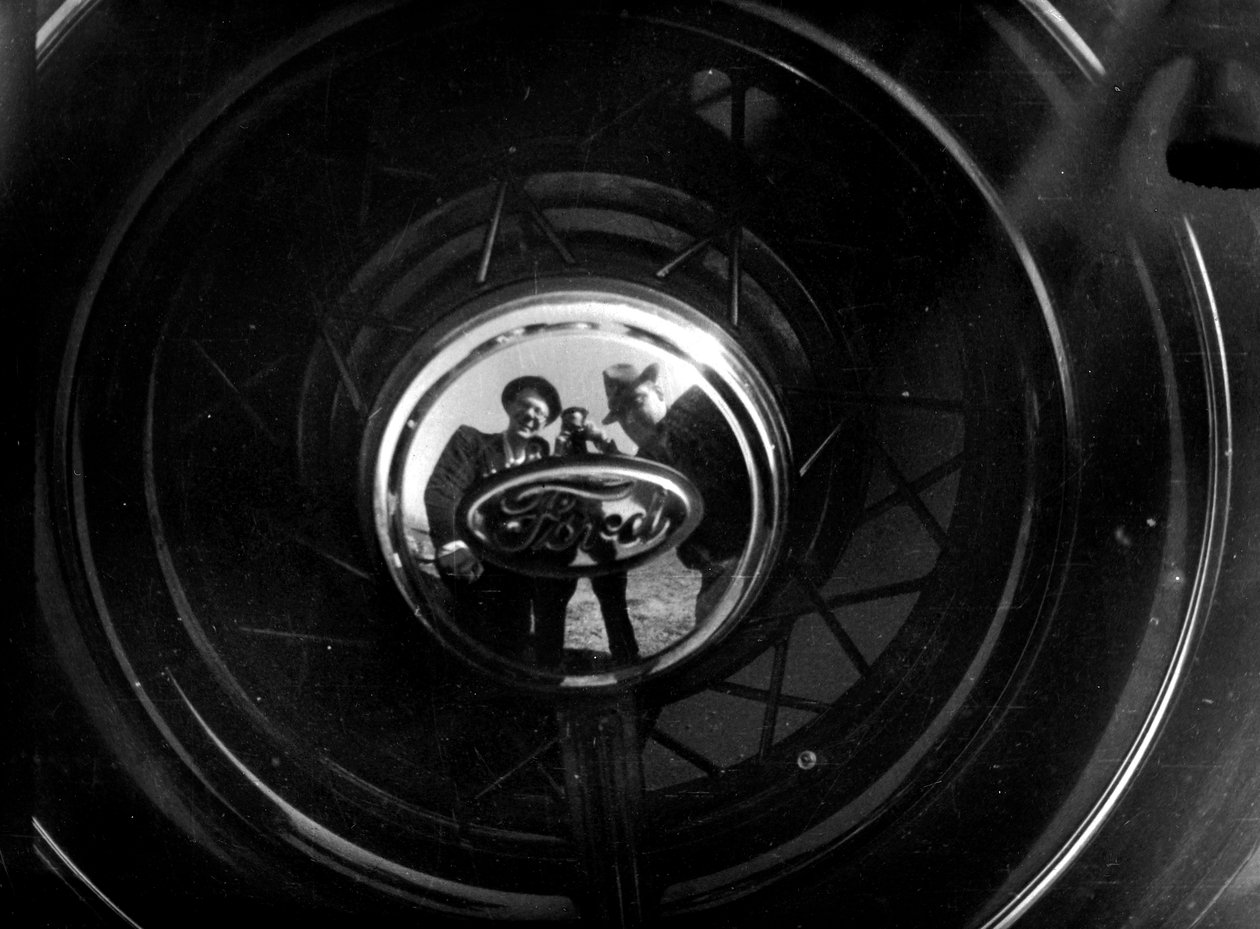 Algunas personas se reflejan en un tapacubos de Ford de Luigi Leoni