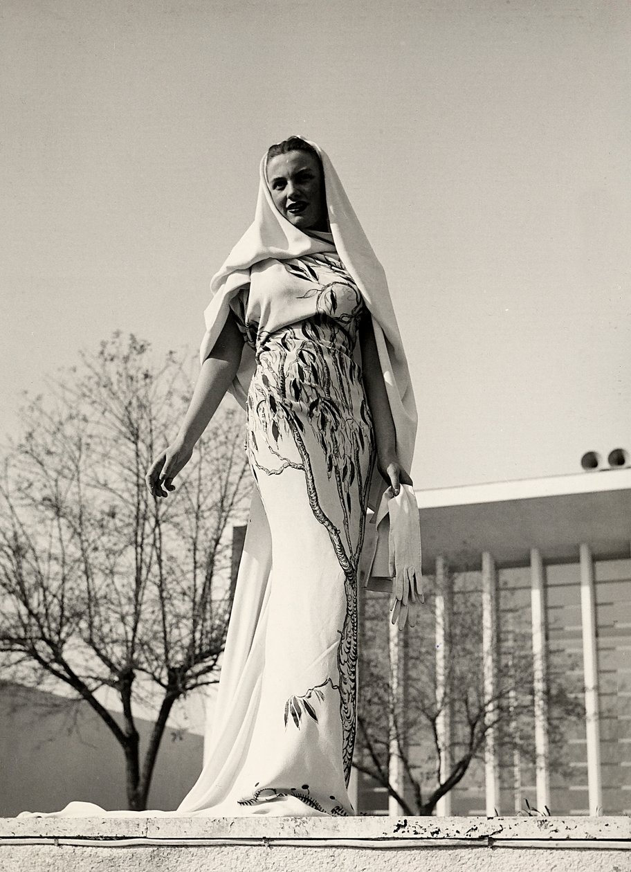 Modelo con vestido de noche de tela estampada floral, creado por la casa de alta costura "Lamma". El artículo se completa con un largo velo. de Luis Bogino
