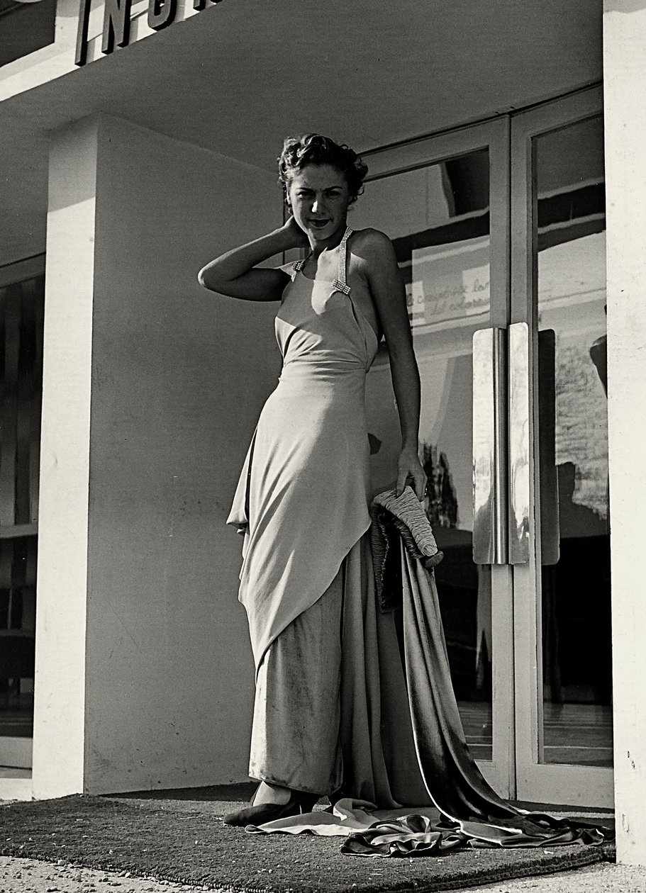 Modelo en vestido de noche creado por la casa de alta costura "Graldi". El artículo se caracteriza por un escote pronunciado adornado con tirantes de pedrería y una larga cola. de Luis Bogino