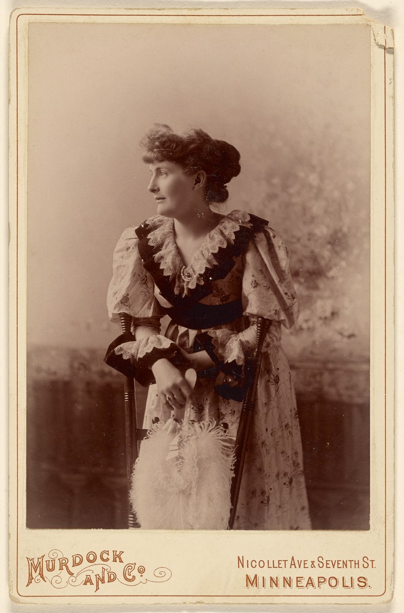 [Mujer no identificada de perfil, apoyada en una silla, sosteniendo un abanico de plumas] de Murdock and Company