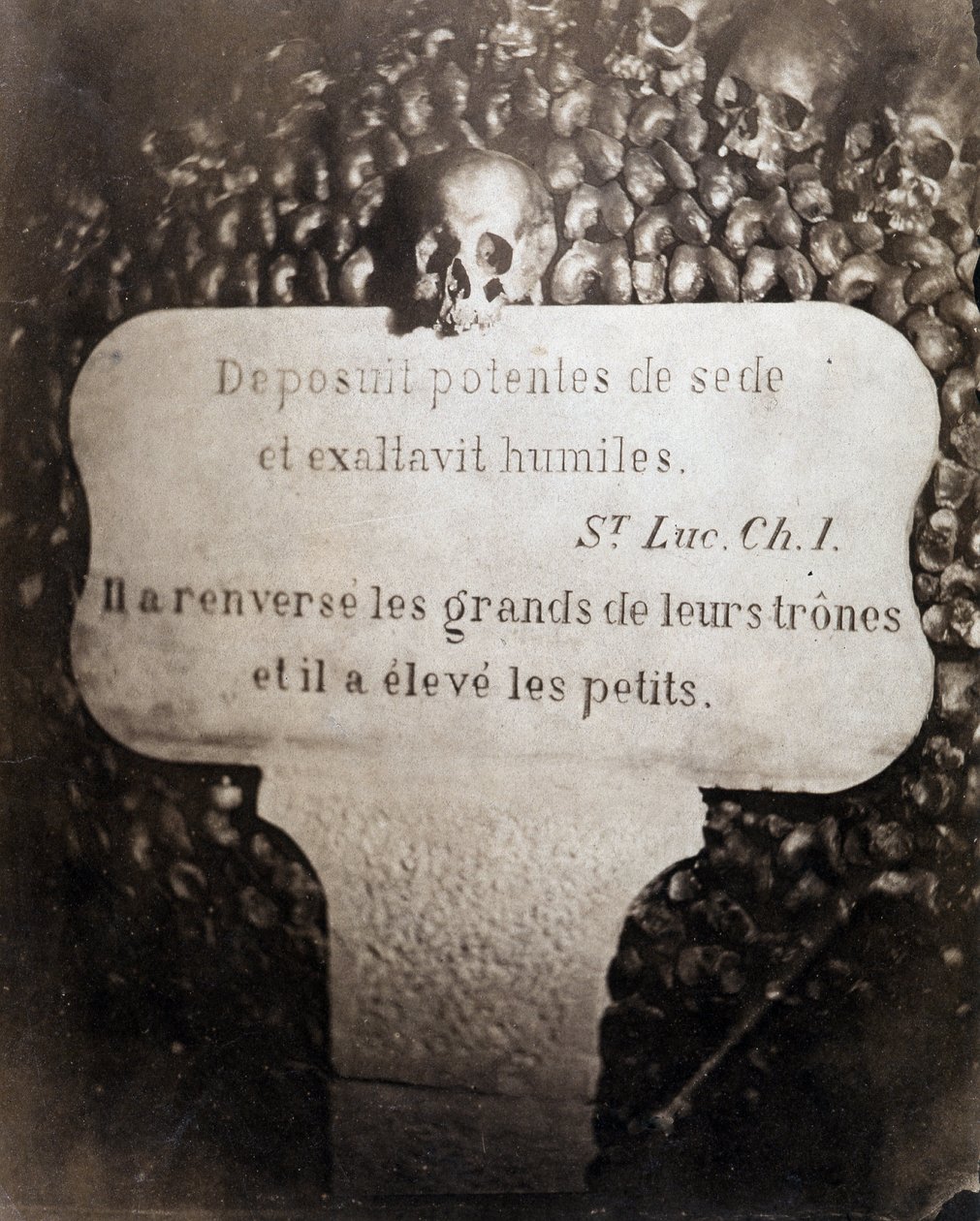 Los osarios de las catacumbas de París. Pedro con una cita del Capítulo 1 del Evangelio de San Lucas (Deposuit potentes de sede et exaltavit humiles. En francés: Derribó a los poderosos de sus tronos y exaltó a los humildes) de Nadar