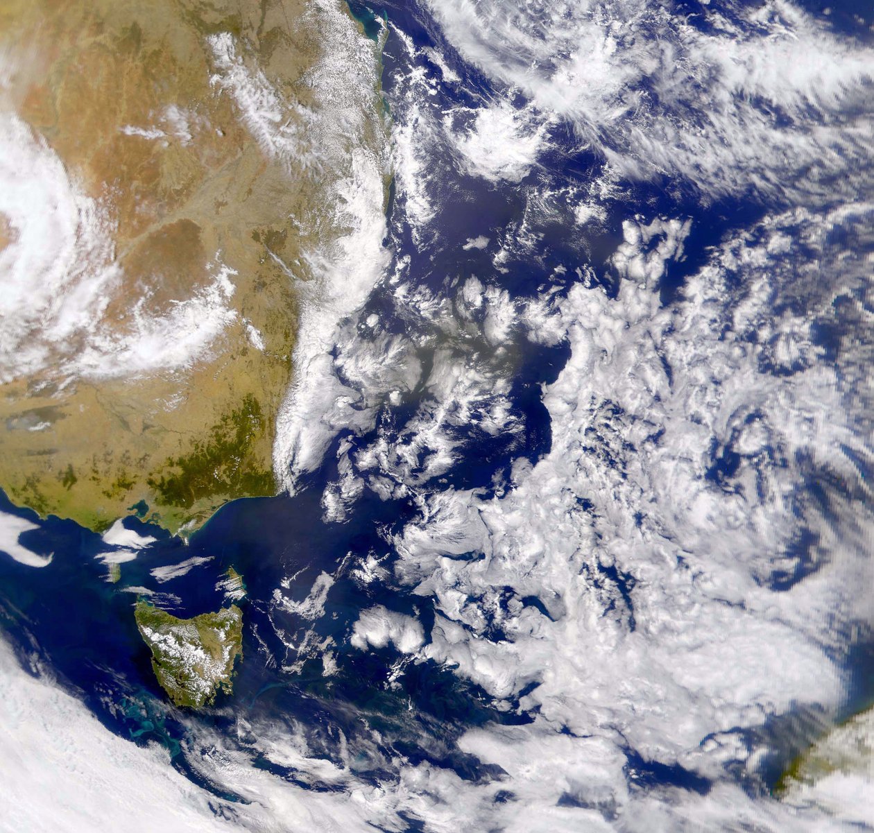 Fotografía satelital del Mar de Tasmania parcialmente cubierto por nubes. A la izquierda está parte de Australia con Tasmania debajo. NASA. Ciencia de National Aeronautics and Space Administration National Aeronautics and Space Administration