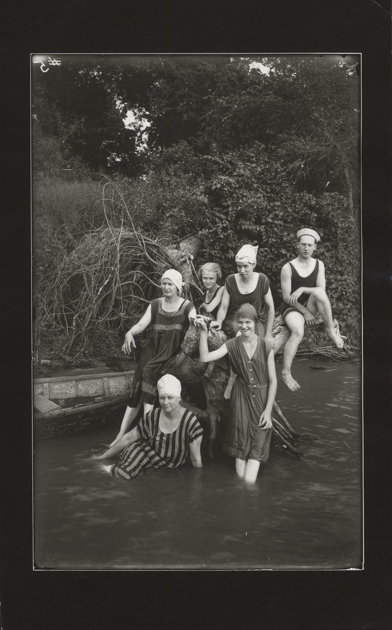 Grupo de un hombre y cuatro mujeres en trajes de baño sentados en la orilla de un río de Oscar C. Kuehn