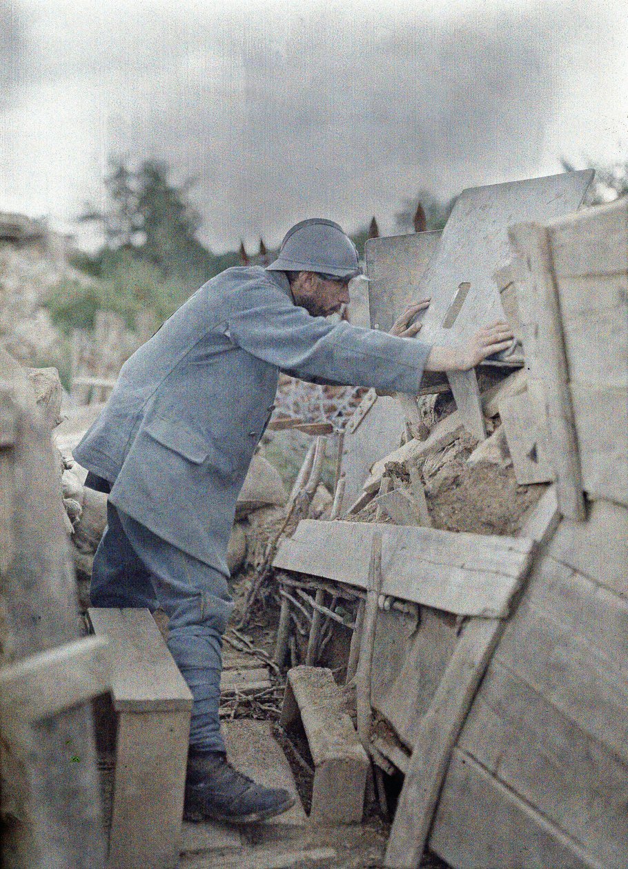 Un soldado francés en el puesto de observación del ejército 26 observando el área frente a él a través de un escudo de metal protector, Eglingen, Departamento Haut-Rhin, Alsacia, Francia, 26 de junio de 1917 (autocromo) de Paul Castelnau