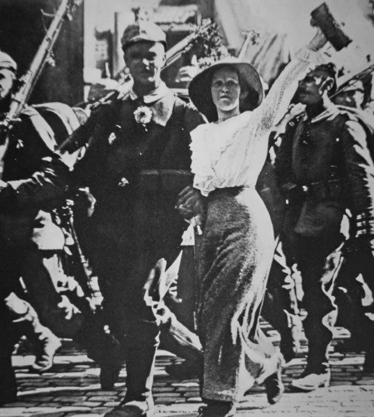 Tropas alemanas de la Primera Guerra Mundial marchando hacia la guerra, sus túnicas y rifles adornados con flores de la multitud jubilosa de Photographer German