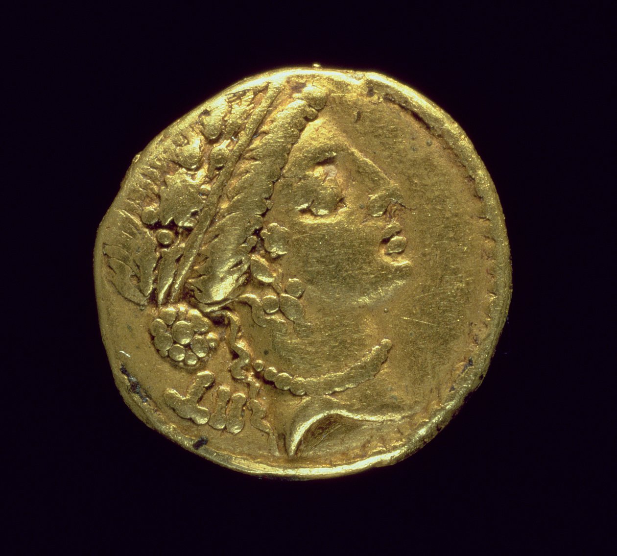 Aureus (anverso) acuñado por Julio César (110-44 a.C.) que representa una cabeza femenina a la derecha con una corona de roble y diadema de Roman