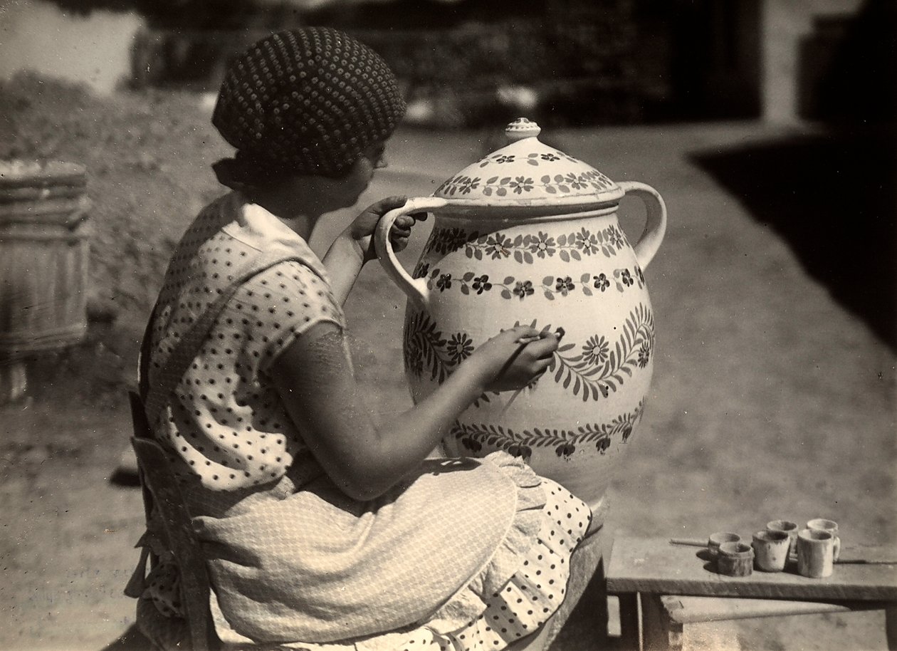 Una dama húngara retratada mientras pinta un ánfora con motivos florales; al lado, sobre un pequeño banco, los pinceles y los vasos con los colores. de Rudolf Balogh