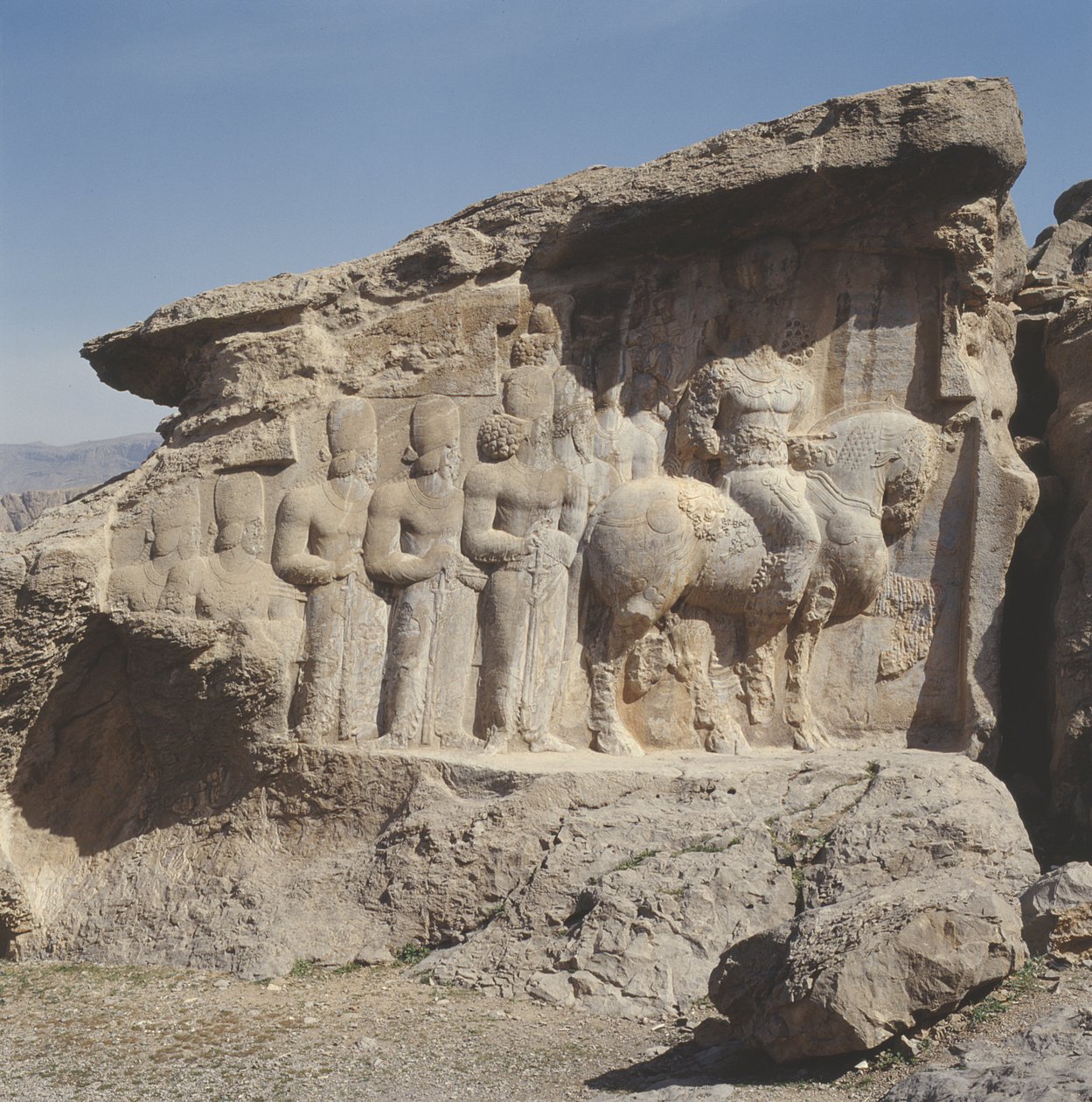 Relieve en roca que representa a Shapur I y su familia con emblemas heráldicos en sus sombreros, con una inscripción trilingüe en el caballo en griego, parto y persa medio de Sasanian