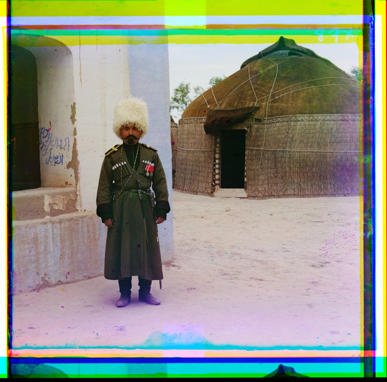 Un hombre armado en uniforme junto a un edificio con una yurta en el fondo, Rusia, 1915 de Sergey Prokudin Gorsky