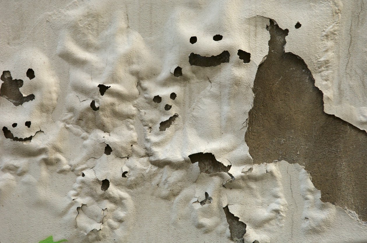 Italia, Toscana, Florencia, Caras sonrientes de fantasmas en una pared pintada a la intemperie, 2022 (foto) de Sisse Brimberg