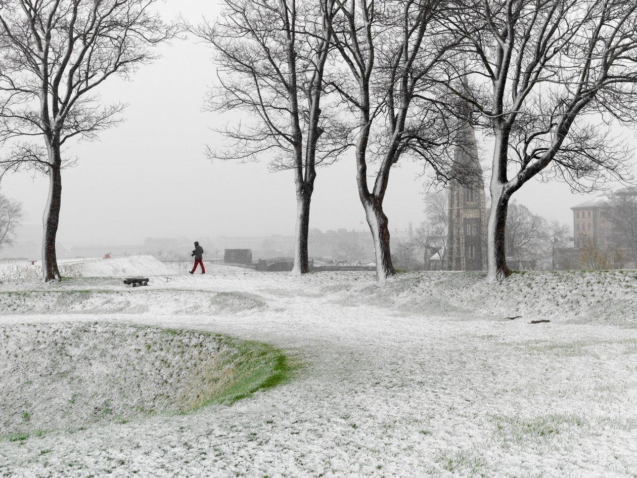 Figura solitaria caminando por la Fortaleza de Copenhague durante una tormenta de nieve, Dinamarca, 2022 (foto) de Sisse Brimberg