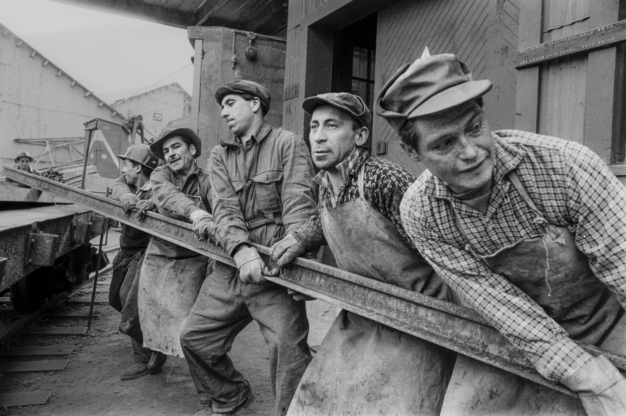 Trabajadores mineros se unen para mover un pesado raíl de acero en la mina de cobre El Teniente en... de Ted Spiegel
