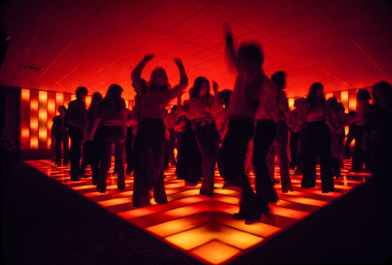 Jóvenes bailarinas en una discoteca bailando en una pista iluminada de Ted Spiegel