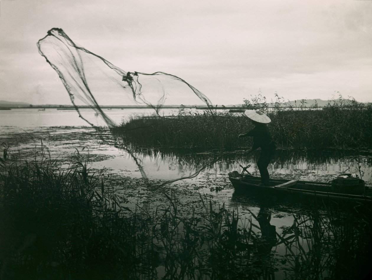 Pescador japonés echando las redes en un lago, hacia 1900 - 1915 (fotografía) de Teijiro Takagi