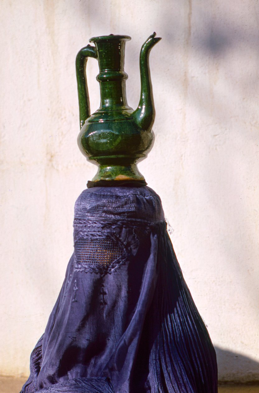 En Kabul, una mujer oculta por un chadri (chador) de seda lleva una jarra... de Thomas J. Abercrombie