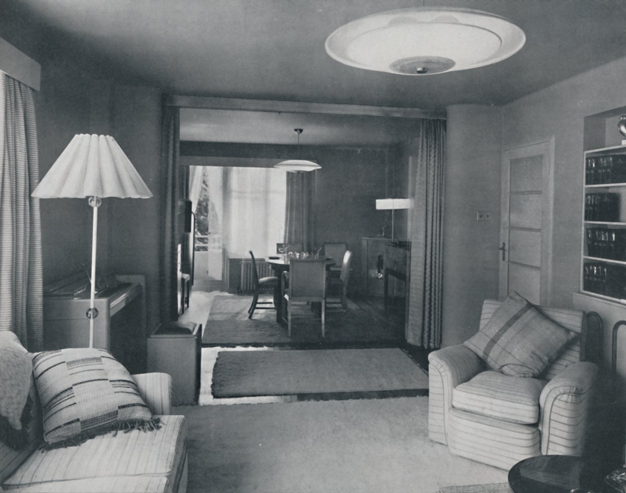 Comedor y sala de estar, divididos solo por cortinas pesadas en un tejido moderno atractivo, 1942 de Unbekannt