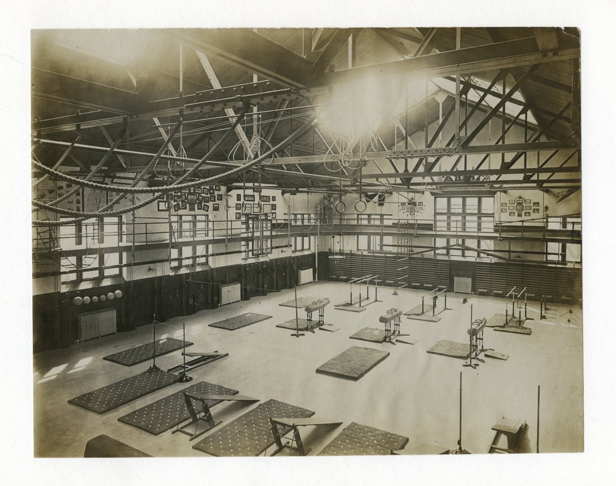 Fotografía horizontal del interior de un gran gimnasio. Equipos y colchonetas están esparcidos por el suelo de Unbekannt