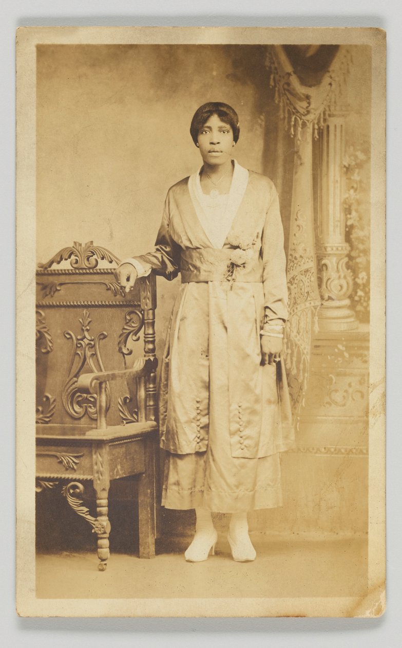 Tarjeta postal fotográfica de una mujer junto a una silla de madera, 1904-1918 de Unbekannt