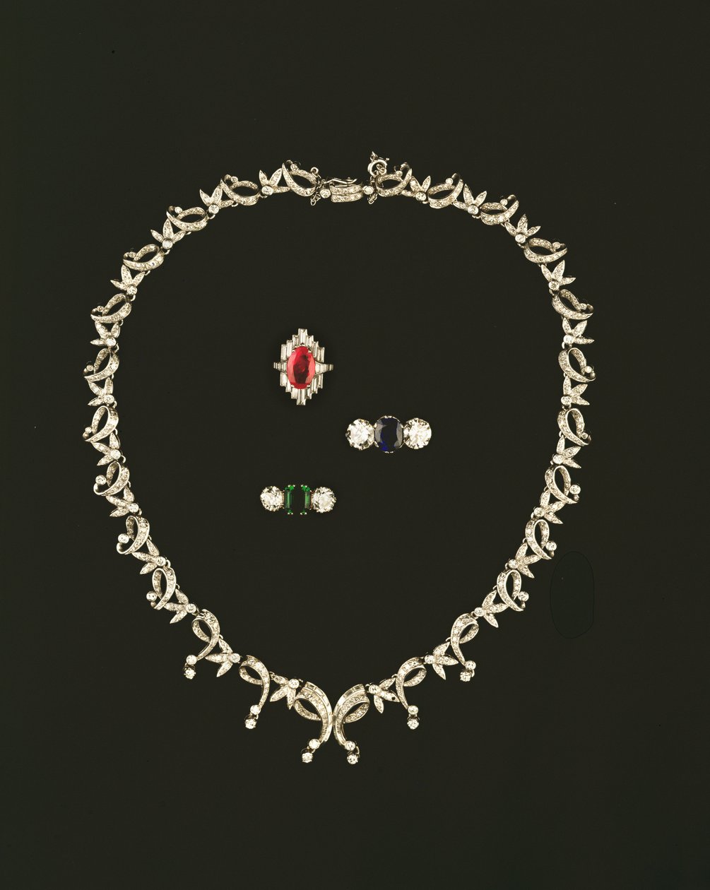 Collar de diseño de pergamino y hojas Art Deco; anillo de racimo de rubíes y diamantes; anillo de tres piedras con zafiro y diamantes; anillo de tres piedras con esmeralda y diamantes de Unbekannt Unbekannt