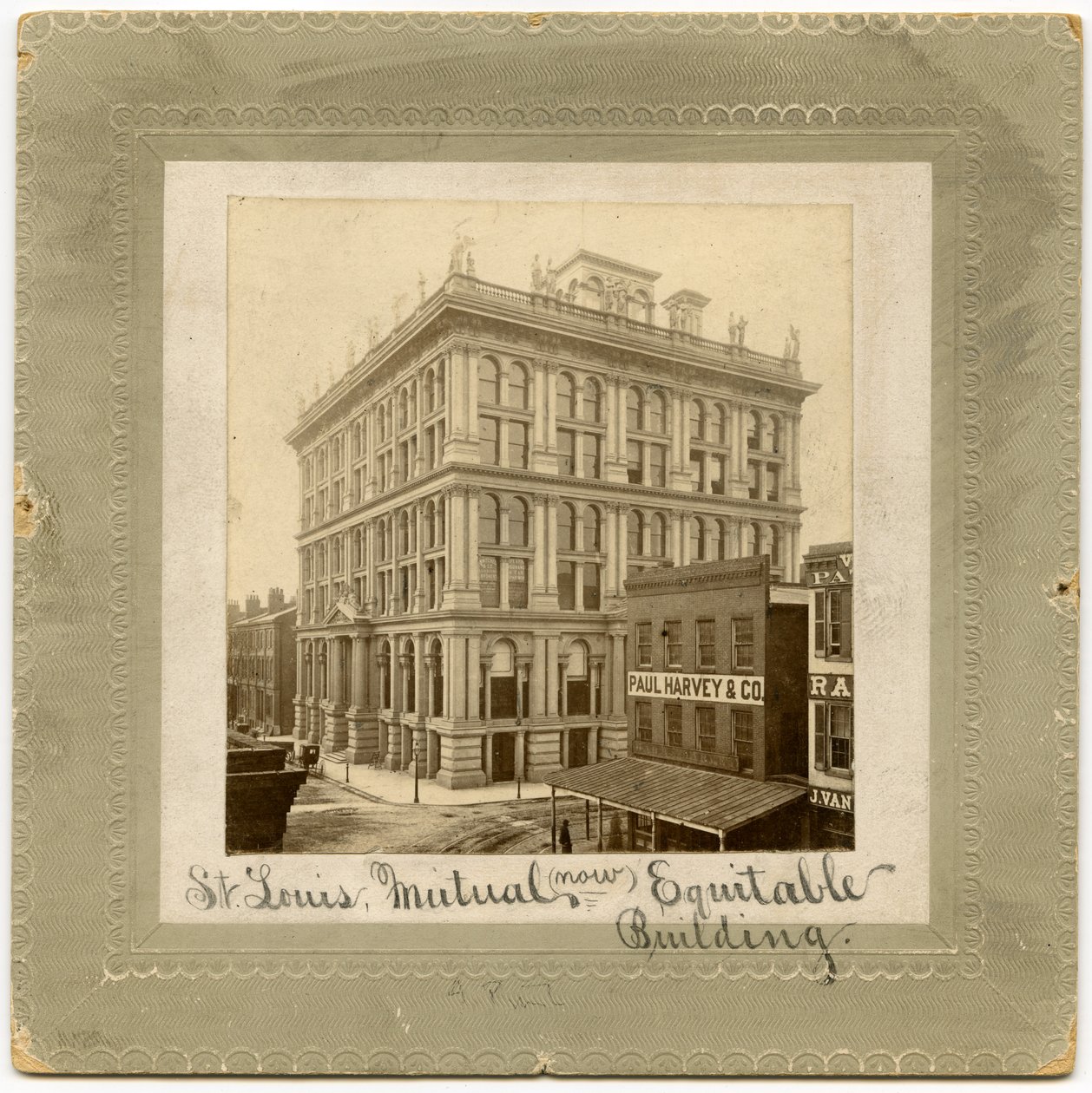 Fotografía de un edificio de seis pisos con figuras en la parte superior. También llamado Edificio de Seguros de Vida de St. Louis de Unknown
