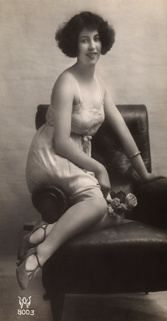 Una joven posa en enaguas, sentada en un sillón de Unknown photographer