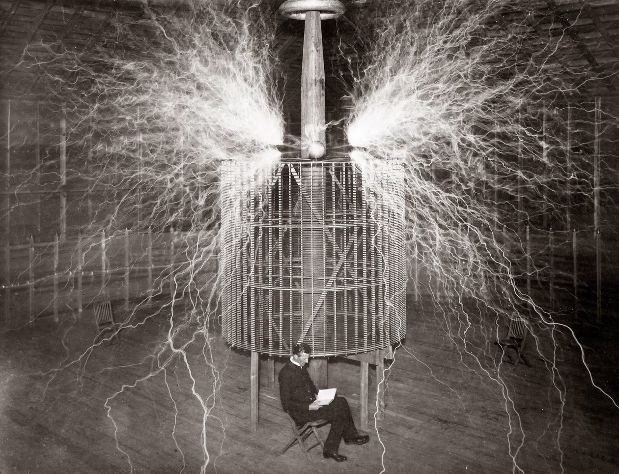 Nikola Tesla sentado en su laboratorio de Colorado Springs con su “Transmisor Magnificante” de Unknown photographer