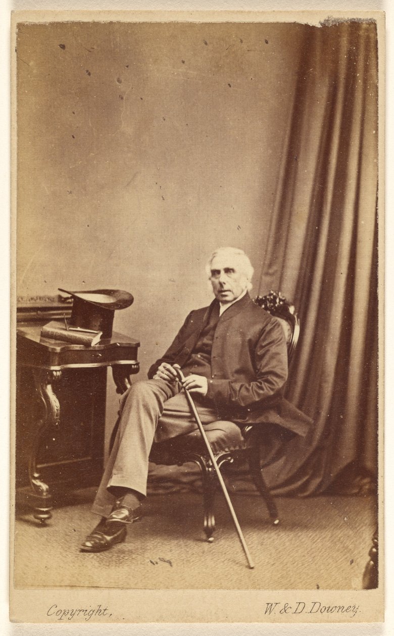 [Hombre de pelo blanco no identificado sentado, con bastón, sombrero de copa y un libro sobre la mesa a la izquierda]. de W. and D. Downey