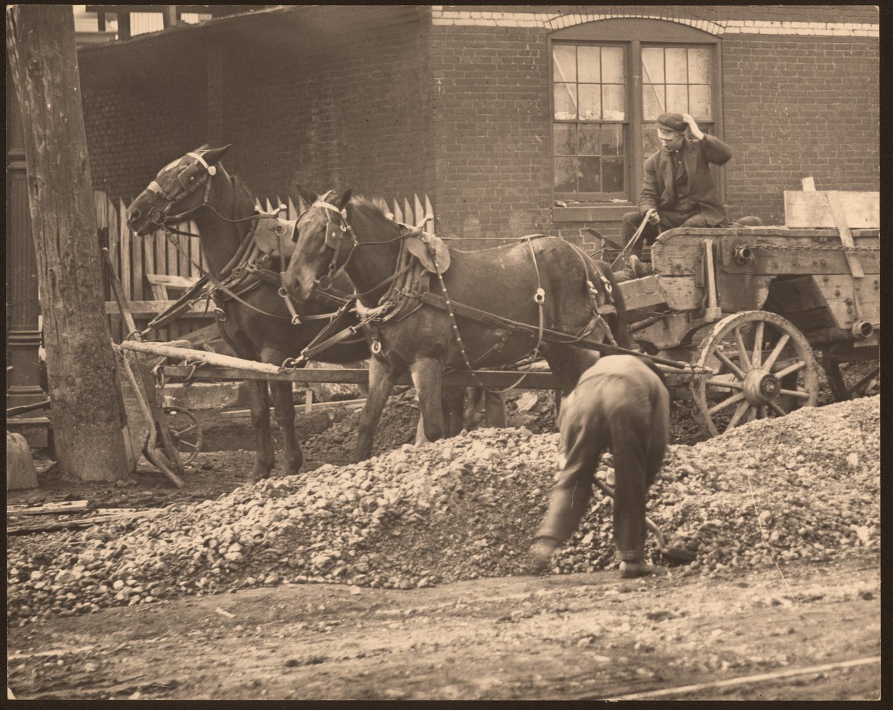 Fotografía horizontal en blanco y negro de un carro tirado por caballos en un sitio de construcción. Un hombre pala tierra y roca mientras otro conduce el carro de William G. Swekosky