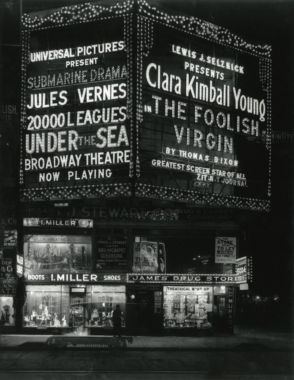 1554 Broadway en la calle 46, I. Miller Shoes; James Drug Store, y grandes marquesinas para películas iluminadas arriba. de William Davis Hassler
