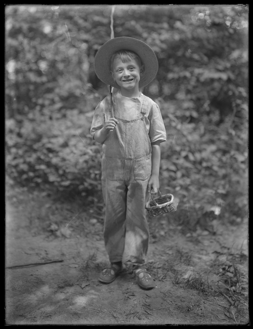 William Gray Hassler con sombrero de paja y overol, llevando una caña de pescar y una cesta en el bosque, 20 de agosto de 1911 de William Davis Hassler