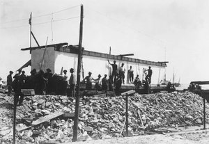 Varios hombres alrededor de un enorme bloque de mármol ya cuadrado, recién transportado al valle desde las canteras en los Alpes Apuanos (foto en blanco y negro)