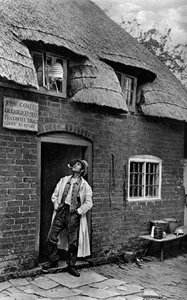 Un hombre fumando una pipa fuera de una tienda, Worcestershire, c1922
