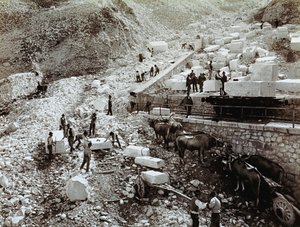 Estación de tren con trabajadores cargando bloques de mármol en vagones de tren, se ven tres pares de bueyes con carros de transporte (foto en b/n) de Fratelli Alinari