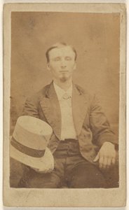 [Hombre no identificado con perilla sentado, sosteniendo un sombrero de copa de color claro en la rodilla]