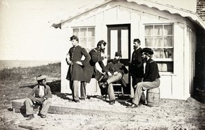 Cinco soldados de la Guerra Civil reunidos en el porche de tierra fuera de una casa, joven afroamericano sentado cerca de ellos, 1861-65 de American Photographer