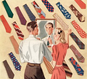 Un hombre se endereza la corbata en el espejo en medio de un despliegue de corbatas de muchos hombres de American School