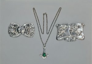 Joyería de plata diseñada para Liberty. De izquierda a derecha: Broche de cintura con diseño celta entrelazado, 1904. Colgante y cadena con crisoprasa tallada en cabujón. Broche de cintura con diseño repujado en martillado