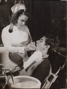 [Higienista dental inspecciona la boca de un paciente]