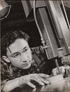 [Hombre con gafas trabaja atentamente con una lima industrial] de Arnold Eagle