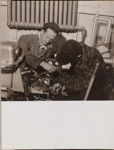 [Dos hombres trabajan en una máquina utilizando un destornillador y una llave inglesa] de Arnold Eagle